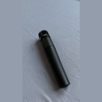 Černý dynamický mikrofon s matným povrchem. Na horní části těla je bílý nápis SM57. Mikrofon má na vrcholu černou mřížku.