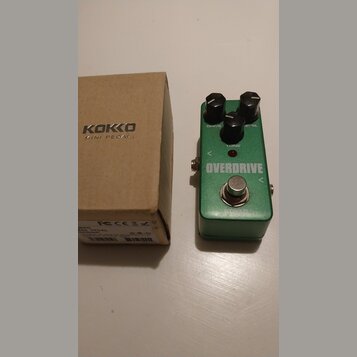 Zelený efekt pedál s nápisem OVERDRIVE a tři černé ovládací knoflíky s popisky DRIVE, LEVEL a TONE. Nad nápisem se nachází malá červená kontrolka. Ve…