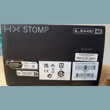 Černá papírová krabice s bílými nápisy HX STOMP a LINE 6. Na pravé straně je vytištěno číslo 50-50-0221 a dvě nálepky; první obsahuje text PN: 99-080…