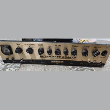 Zlatý basový zesilovač s černými ovládacími knoflíky a analogovým VU metrem vlevo. Na předním panelu jsou nápisy ULTRABASS BX4410, 450-WATT BASS AMPL…