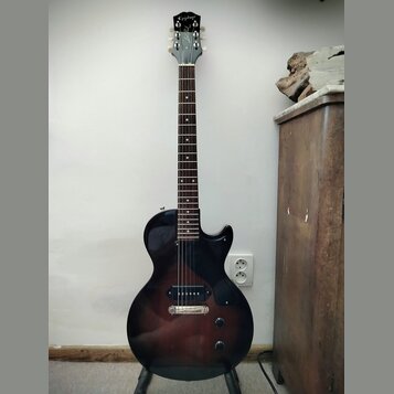 Elektrická kytara s tmavě hnědým gradientem (sunburst) a černým hmatníkem. Na hlavě je bílý nápis Epiphone. Nástroj má dva humbuckery, jeden tónový a…