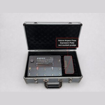 V otevřeném hliníkovém kufru s černým vnitřním polstrováním se nachází šedý kytarový efektový pedalboard a expresní pedál. Na horní části přístroje j…