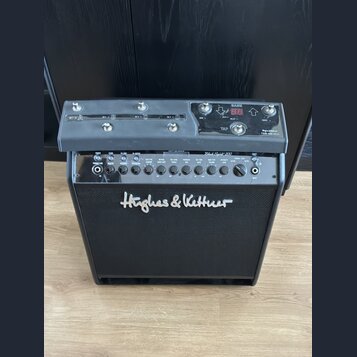 Černý kytarový kombozesilovač s nápisem Hughes & Kettner na předním textilním krytu. Horní ovládací panel obsahuje digitální displej s nápisem BANK a…