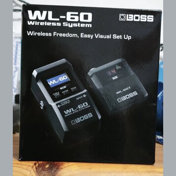 Fotografie znázorňuje krabici od bezdrátového systému s nápisy WL-60 Wireless System a BOSS. Na obalu jsou zobrazeny dvě černé jednotky, jedna s nápi…