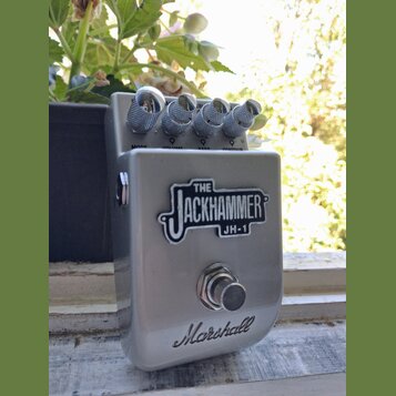 Stříbrný efekt pedál s kovovým povrchem. Na přední straně je nápis THE JACKHAMMER JH-1 a ve spodní části logo Marshall. V horní části jsou čtyři kovo…