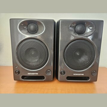 Dva identické studiové monitory v tmavě šedém lesklém provedení. Každý reproduktor má v horní části menší výšký reproduktor a ve spodní části větší b…