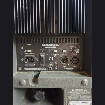 Zadní panel černého aktivního reproduktoru značky MACKIE, model SRM450. Na panelu jsou nápisy ACTIVE SOUND REINFORCEMENT SYSTEM, DESIGNED BY MACKIE I…