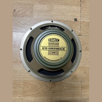 Kruhový reproduktor s kovovým rámem v béžovém odstínu a černou membránou. Uprostřed je žlutý štít s nápisy CELESTION LOUDSPEAKERS, G10 GREENBACK a 30…