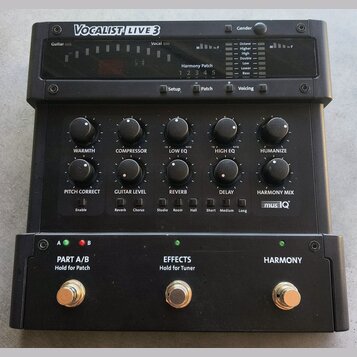 Černý procesor vokálních efektů s nápisem VOCALIST LIVE 3. Zařízení obsahuje několik otočných potenciometrů s popisky WARMTH, COMPRESSOR, LOW EQ, HIG…