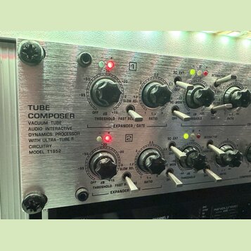 Detailní pohled na přední panel stříbrného rackového zařízení s nápisem TUBE COMPOSER VACUUM TUBE AUDIO INTERACTIVE DYNAMICS PROCESSOR WITH ULTRA-TUB…