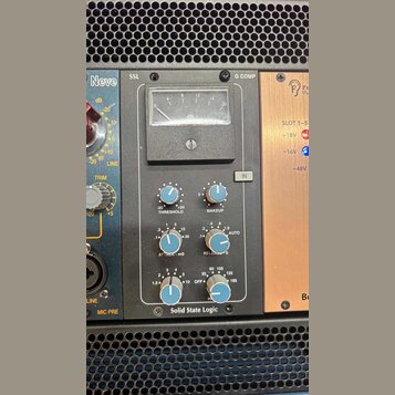 Stupňovitý rackový procesor v šedém kovovém provedení. Na horní hraně jsou nápisy SSL a G COMP, v dolní části nápis Solid State Logic. Zařízení obsah…