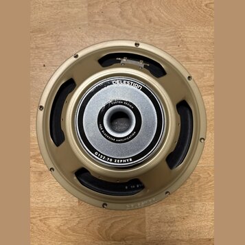Fotografie znázorňuje reproduktor s kovovým rámem v zlatavé barvě. Na středovém magnetu je bílý nápis CUSTOM DESIGN a FOR BLACKSTAR AMPLIFICATION, po…