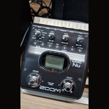 Černý efektový pedál značky ZOOM, model G2 Nu. Zařízení obsahuje displej, tři ovládací knoflíky s popisky PARM 1, PARM 2 a PARM 3, několik tlačítek a…