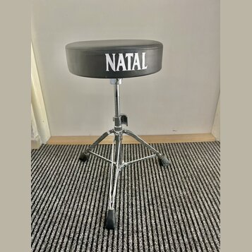 Černý bubeníckýstolek s kulatým polstrovaným sedadlem. Na přední straně sedadla je bílý nápis NATAL. Nohy a středový sloupek jsou vyrobeny z chromova…