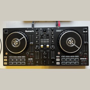Černý DJ kontrolér značky Numark s nápisem PERFORMANCE DJ CONTROLLER a označením MIXTRAK PRO FX. Zařízení obsahuje dva velké jog-kola s bílým logem u…