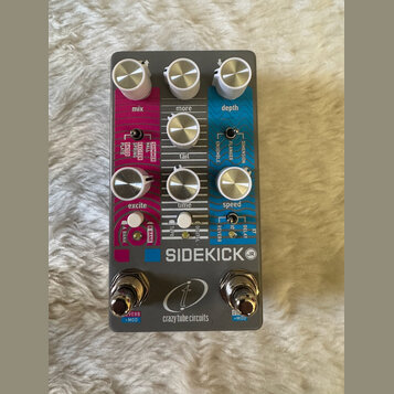 Šedý efekt pedál s barevnými sekcemi v růžové, bílé a modré barvě. Na zařízení jsou nápisy „SIDEKICK (JR)“ a „crazy tube circuits“ s doprovodným loge…