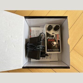 V bílé krabici se nachází efekt pedál s bílým povrchem a černými ovládacími knoflíky. Na pedálu je nápis PITCH FORK, logo electro-harmonix a označení…