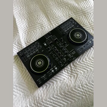 Černý DJ kontrolér s dvěma jog-koly a centrálním mixážním sekcí. Na horní části je bílé logo Pioneer DJ a v pravé části nápis DDJ-400. Povrch přístro…