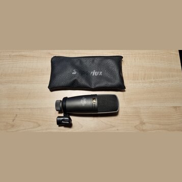 Na fotografii je černý dynamický mikrofon s mřížkou a černý kožený pouzdro se zipem. Na těle mikrofonu je nápis „Superlux“ a „PRO-8“. Na pouzdře i na…