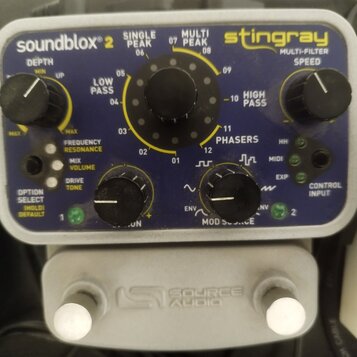 Modrý efekt pedál s nápisy soundblox 2 a stingray MULTI-FILTER. Na horní části jsou ovládací knoflíky DEPTH a SPEED, uprostřed velký volič s označení…