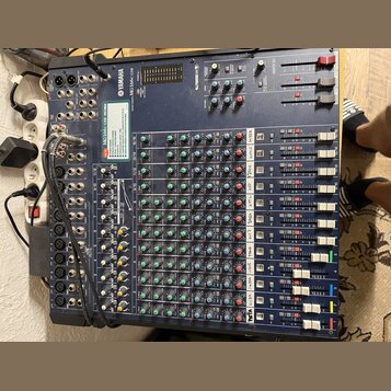 Modrý mixážní pult značky YAMAHA s označením MG166C USB. Zařízení obsahuje řadu vertikálních kanálů s knoflíky v červené, zelené a žluté barvě a fade…