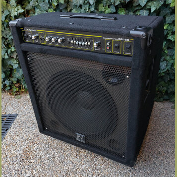 Černý basový kombozesilovač s látkovým potahem a kovovou mřížkou před reproduktorem. Na horním ovládacím panelu je nápis Beta Alvin a BASS AMPLIFIER…
