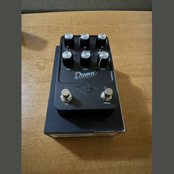 Černý efekt pedál s nápisy Dream a 65 REVERB-AMP. Obsahuje šest ovládacích knoflíků s popisky BASS, TREBLE a BOOST, tři přepínače a dva stisknuté spí…