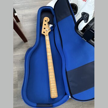 Fotografie zachycuje hmatník a hlavu basové kytary v modrém polstrováním obalu. Na hlavě nástroje je nápis „Burny BASS“ a logo „Fernandes“. Hmatník j…