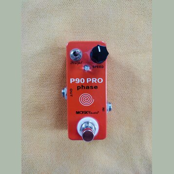 Oranžový efekt pedál s kovovým povrchem. Na přední straně jsou nápisy P90 PRO phase, MOSKYAudio®, SPEED a OUT. V horní části je jeden černý ovládací…