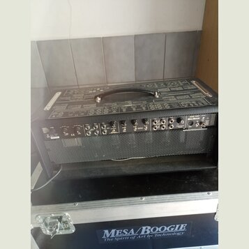 Černý kytarový kombozesilovač s kovovou mřížkou reproduktoru. Na ovládacím panelu je vpravo nápis MESA/BOOGIE a nad ním MARK FIVE. Zařízení stojí na…