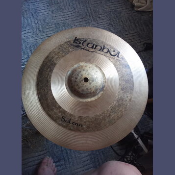 Kruhová mosazná činely s viditelným rýhováním. Na povrchu je nápis „istanbul Mehmet Handmade Cymbals from Turkey“ a v dolní části označení „Sultan“.…
