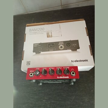 Červený basový zesilovač s nápisy BAM200, INPUT, GAIN, BASS, MIDDLE, TREBLE a MASTER. Na předním panelu je logo tc electronic a text CLASS-D BASS AMP…