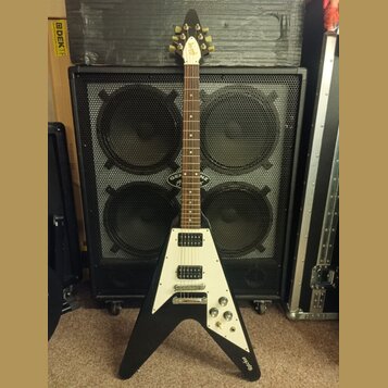 Černá elektrická kytara s bílým pickguardem a Flying V tvarem těla. Na hlavě je viditelné logo "Gibson". Na spodní části těla je nápis "Epiphone". Ky…