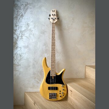 Elektrická basová kytara s přírodním dřevěným povrchem těla a hmatníkem. Na hlavě je viditelné logo ve tvaru motýla. Instrument má černý pickguard, č…