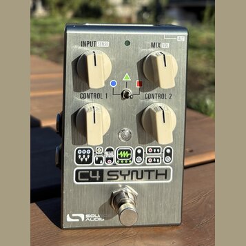 Kovový efekt pedál stříbrné barvy s nápisem C4 SYNTH a logem SOURCE AUDIO v dolní části. Zařízení má čtyři krémové ovládací knoflíky s popisky INPUT…