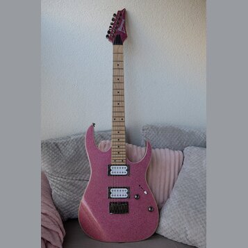 Elektrická kytara s růžovým třpytivým povrchem a světlým hnedým hnedým hmatníkem. Na hlavě je viditelný nápis Danelectro. Nástroj má dva snímače typu…
