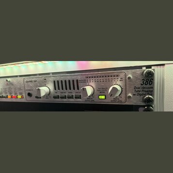Stříbrný rackový předzesilovač s kovovým povrchem. Na pravé straně je nápis 386 Dual Vacuum Tube Preamp w/ Digital Out. Zařízení obsahuje dva ovládac…