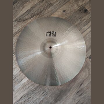 Kruhový kovový činel s kovaným povrchem a viditelnými důlky. Na horní části je černý nápis pAiste GIANT BEAT. Povrch vykazuje mírné známky používání…
