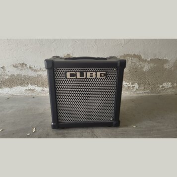 Černý kytarový kombozesilovač s kovovou mřížkou reproduktoru. Na horní části mřížky je bílý nápis CUBE. Nástroj má v horní části přenosnou rukojeť a…