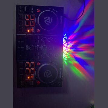 Černý DJ kontrolér s dvěma jog-koly a ovládacími prvky. Na přístroji jsou viditelný nápisy Numark, PARTY MIX a čísla 1 a 2. Některá tlačítka jsou pod…