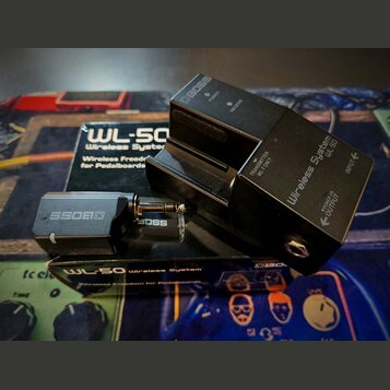 Černý bezdrátový systém WL-50 Wireless System značky BOSS, který se skládá z přijímače a vysílače. Na přijímači jsou nápisy BOSS, Wireless System WL-…