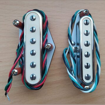 Dvě elektrické snímače typu humbucker s chromovaným krytem a bílými plastovými rámečky. Levý snímač je připevněn na bílou plastovou základnu a má bar…