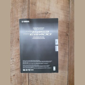 Fotografie znázorňuje černý obal uživatelské příručky. V horní části je bílé logo YAMAHA a nápisy DIGITÁLNÍ KLAVIATURA, DIGITAL KEYBOARD, PSR E453 a…