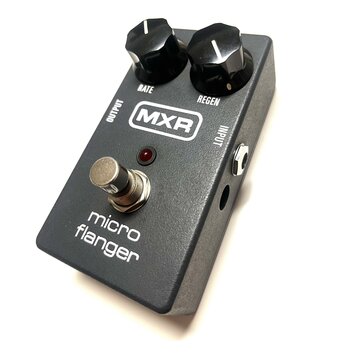 Šedý efekt pedál s nápisem micro flanger a logem MXR. Na horní straně jsou dva černé ovládací knoflíky s popisky RATE a REGEN. V dolní části je umíst…