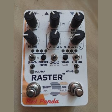 Bílý efekt pedál s nápisy RASTER™, Red Panda a SHIFT. Na horní části jsou šest černých otočných ovladačů s bílými ukazateli a popisy SHIFT, CTRL, DEL…
