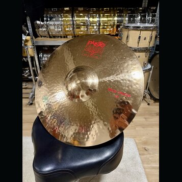 Zlatý kovový činel s kladivovaným povrchem, umístěný na černém polstrovaném sedadle. Na povrchu je červené logo PAiste 2002 s nápisy GRADE 3 ALLOY a…