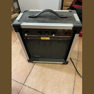 Kytarový kombozesilovač v hliníkovém flightcase s černým povrchem a úchytem. Na horním ovládacím panelu jsou čtyři černé otočné ovladače s popisky GA…