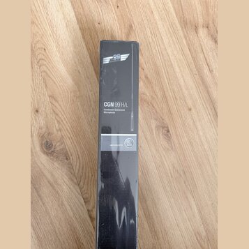 Fotografie znázorňuje úzký černý kartonový obal s produktem uvnitř. Na obalu je bílý nápis CGN 99 H/L a text Condenser Gooseneck Microphone. Ve spodn…