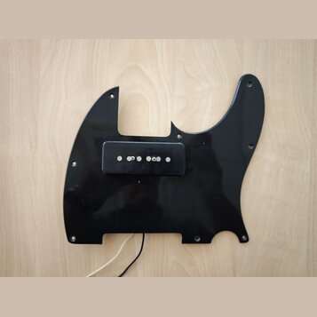 Černý plastový pickguard pro elektrickou kytaru s jedním osazeným snímačem. Snímač je černý a má šest viditelných kovových pólů. Povrch pickguardu je…