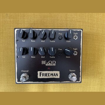 Černý kytarový efekt s bílým vymezením okrajů. Na panelu jsou dva stejné řady ovládacích prvků s popisky Vol, Bass, Mid, Treble, Pres a Gain, doplněn…